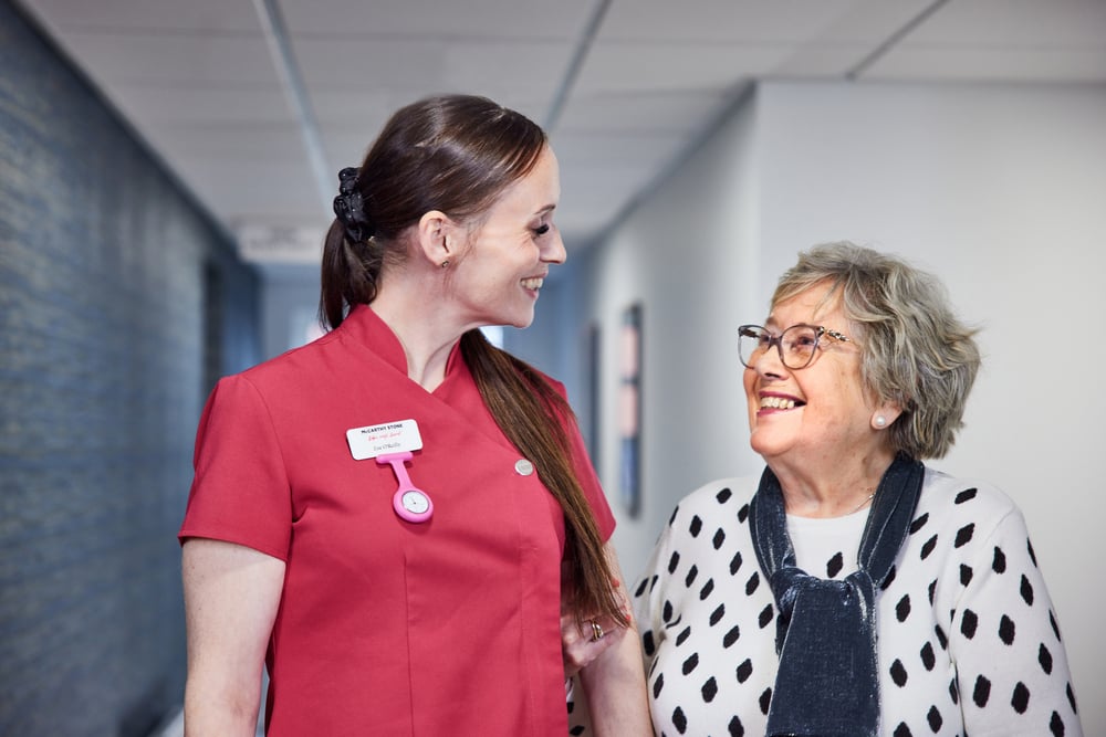 A member of care staff walking and talking with an older lady