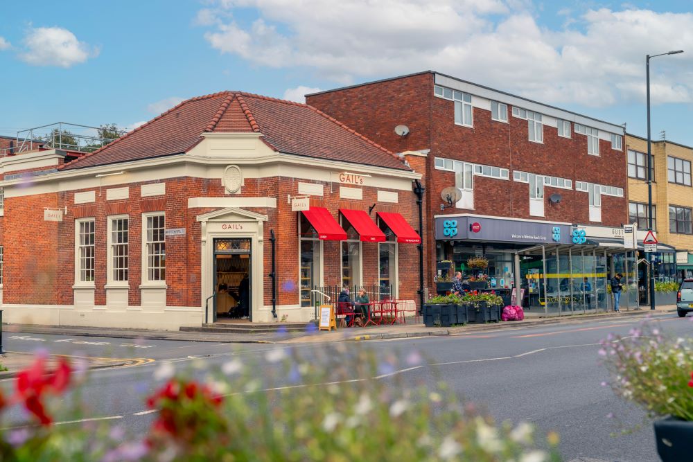 a brick building with a street and people sitting outside