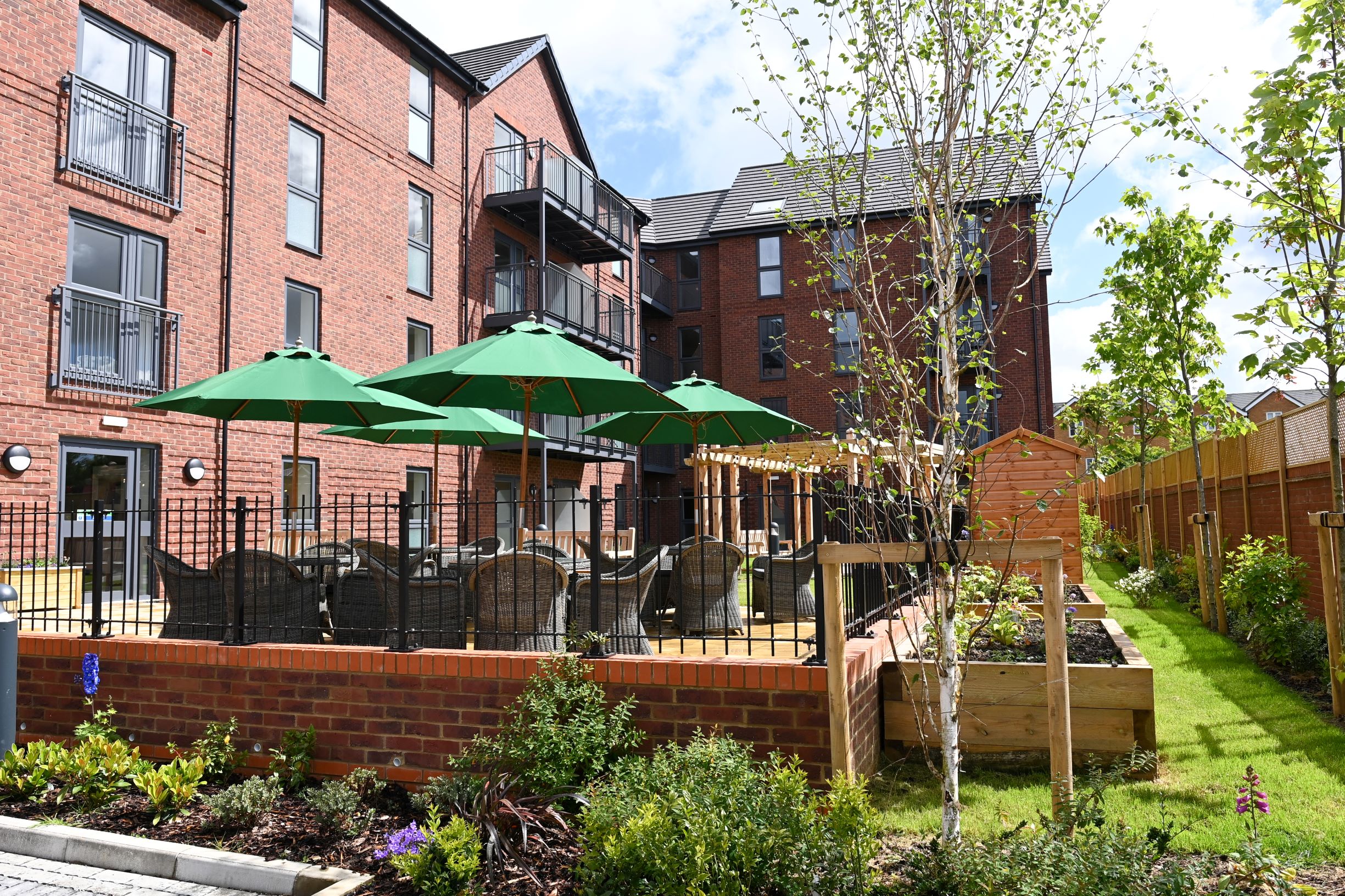 a fenced in yard with umbrellas and a brick building