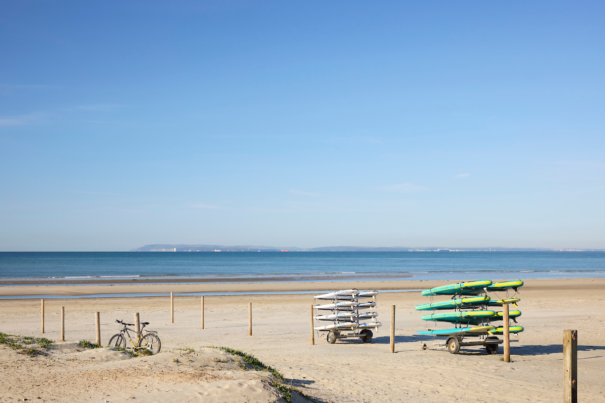 a beach with surfboards and bicycles