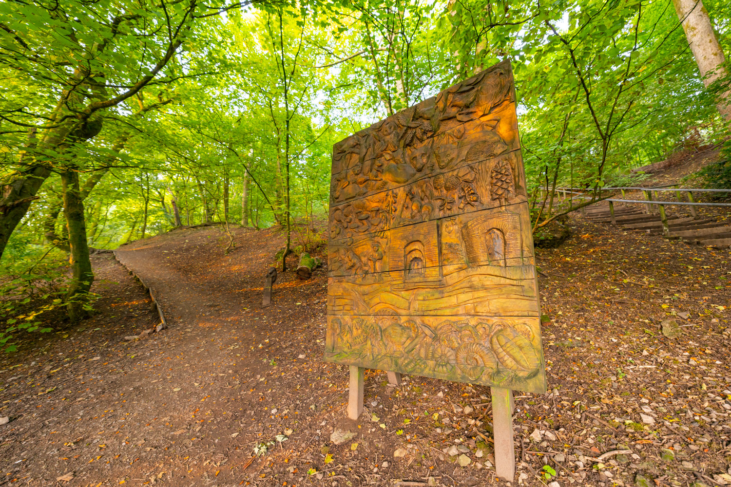 a sign on a path in a wooded area
