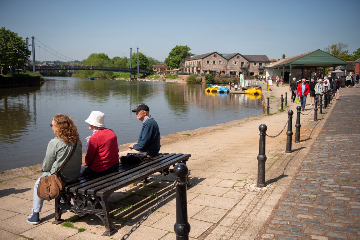 people sitting on a bench by a river