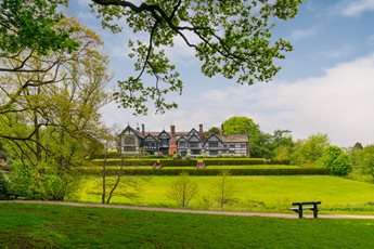 a large house with a lawn and trees in front of it