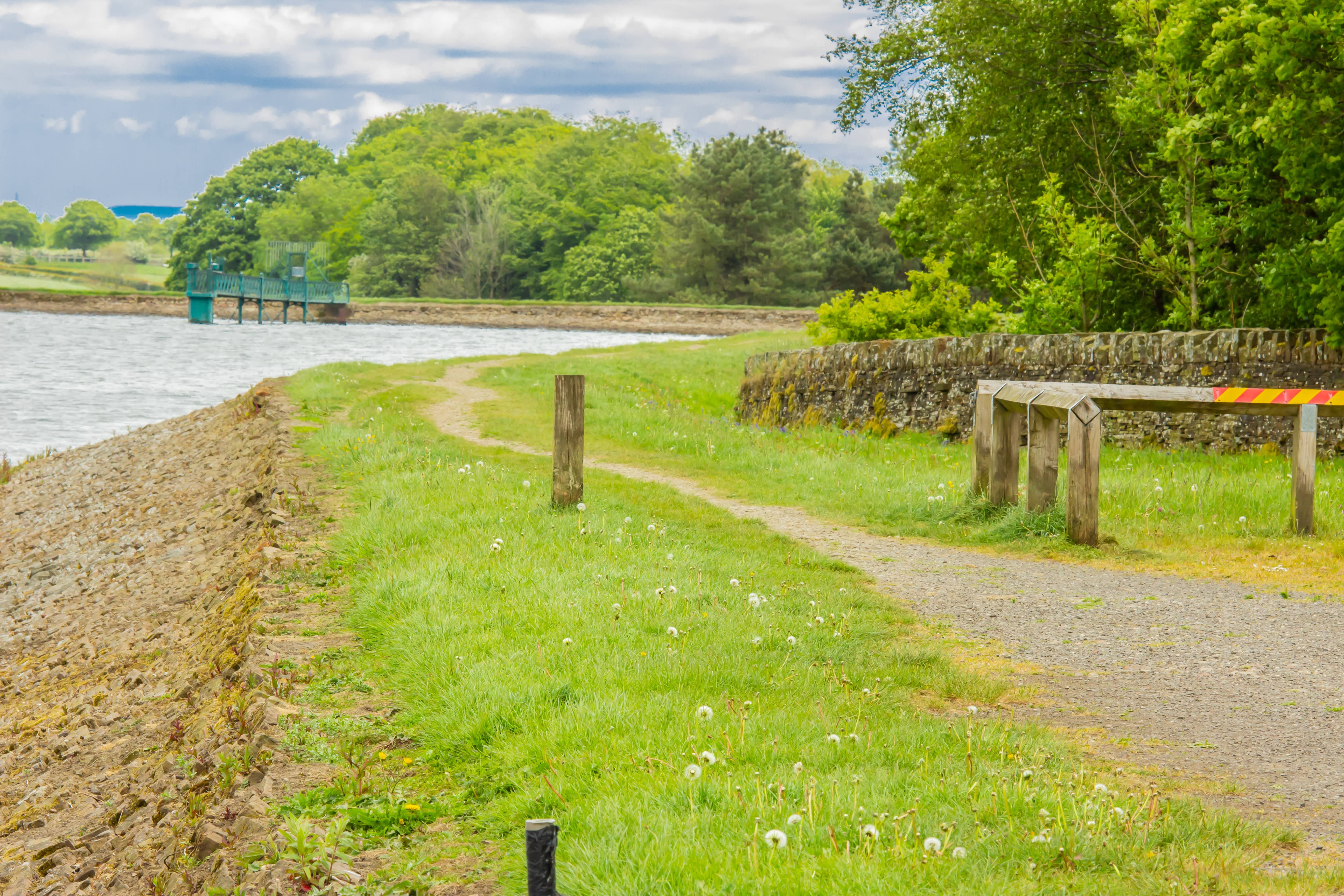 Path with wooden posts leading to Horwich Reservoir on an overcast day