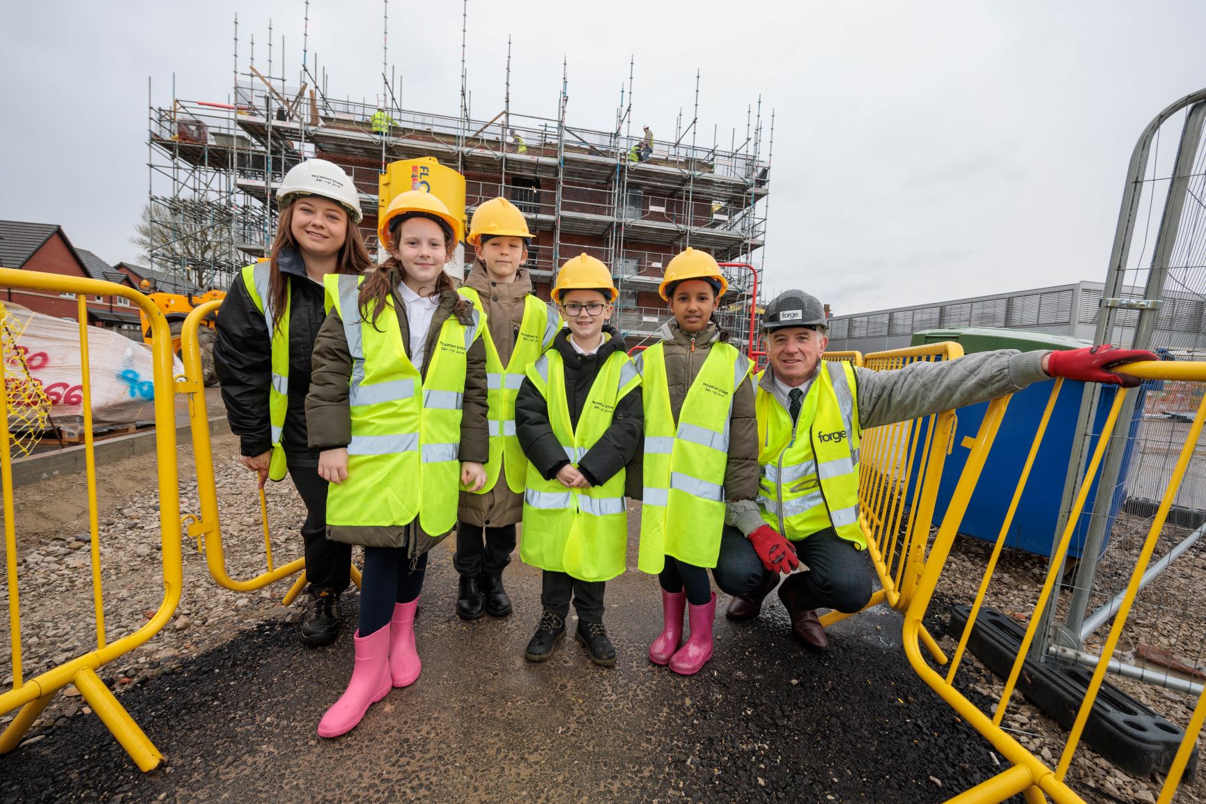 a group of people wearing safety vests and standing next to a yellow machine