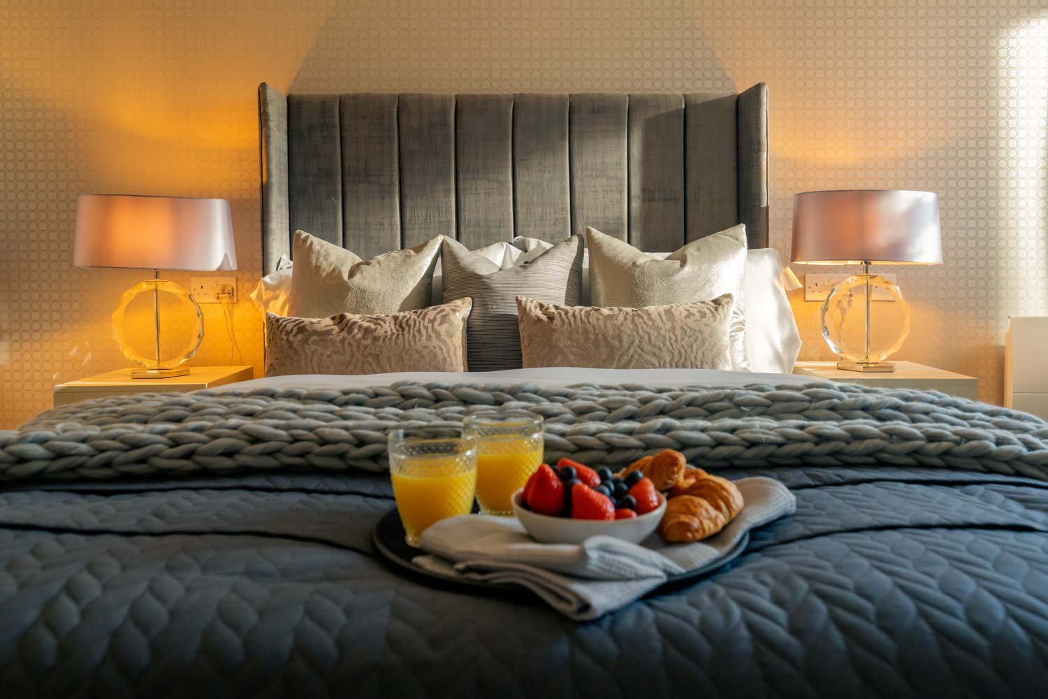 a bed with a tray of fruit and drinks on it