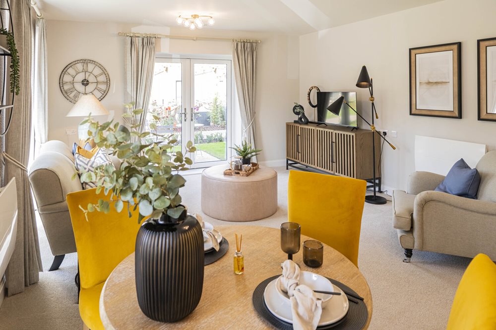 a living room with a yellow chair and a table with a vase with flowers on it