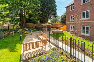 a fenced in yard with a bench and a building