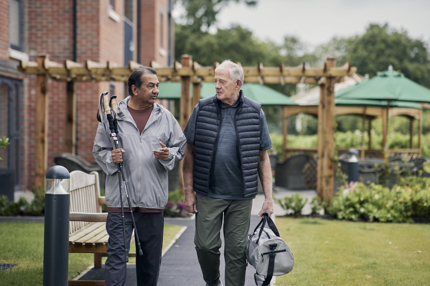 a couple of men walking down a sidewalk holding a pair of canes