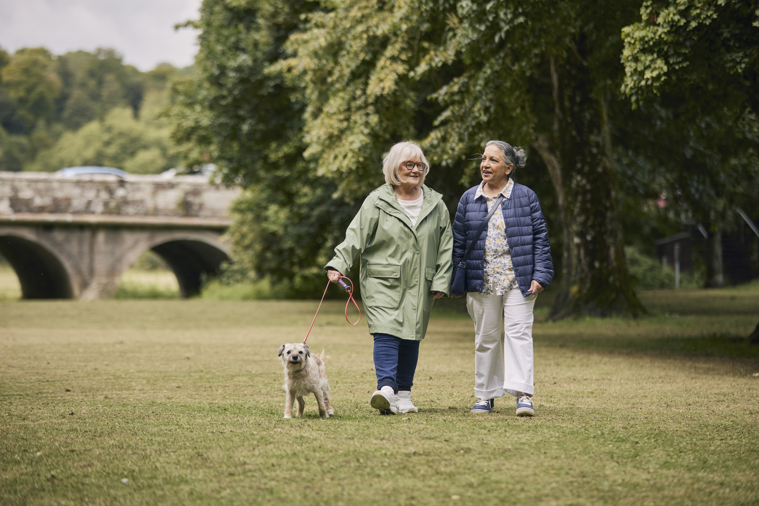 a couple of women walking a dog