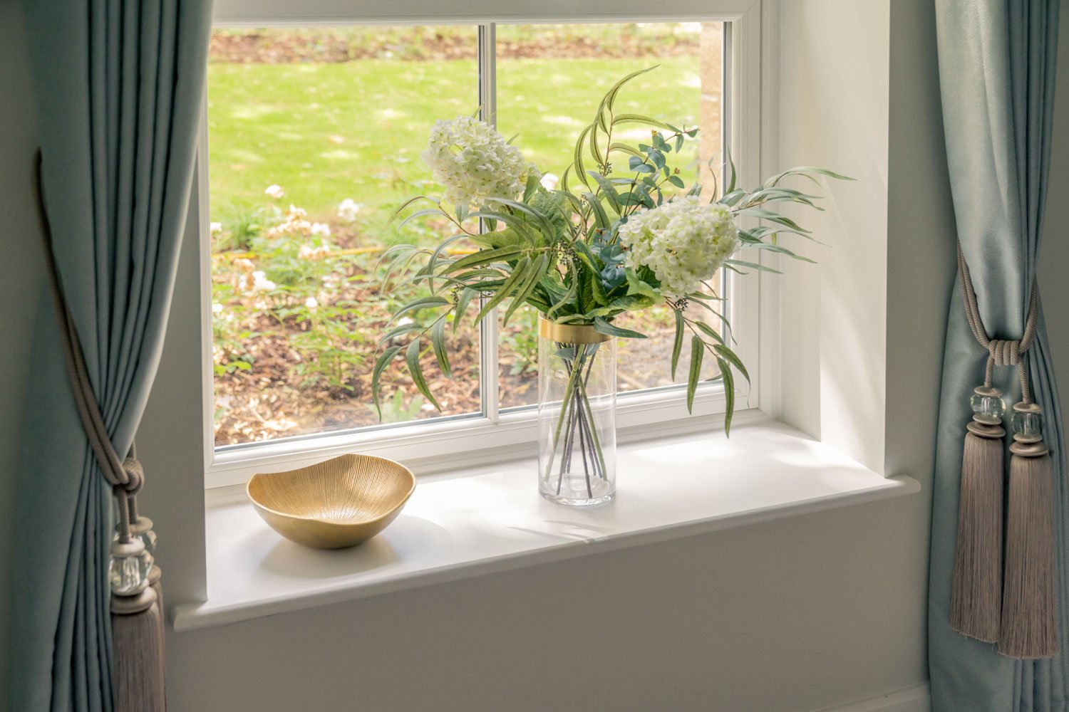 a vase of flowers sits on a window sill