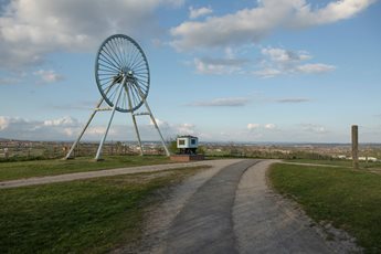 a road with grass and a truck on it and a large ferris wheel in the background