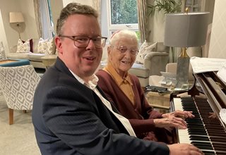 Homeowner Rosemary Chrimes and piano tutor Mikael Petersson playing the piano at Ryland Place Retirement Living PLUS development in Edgbaston