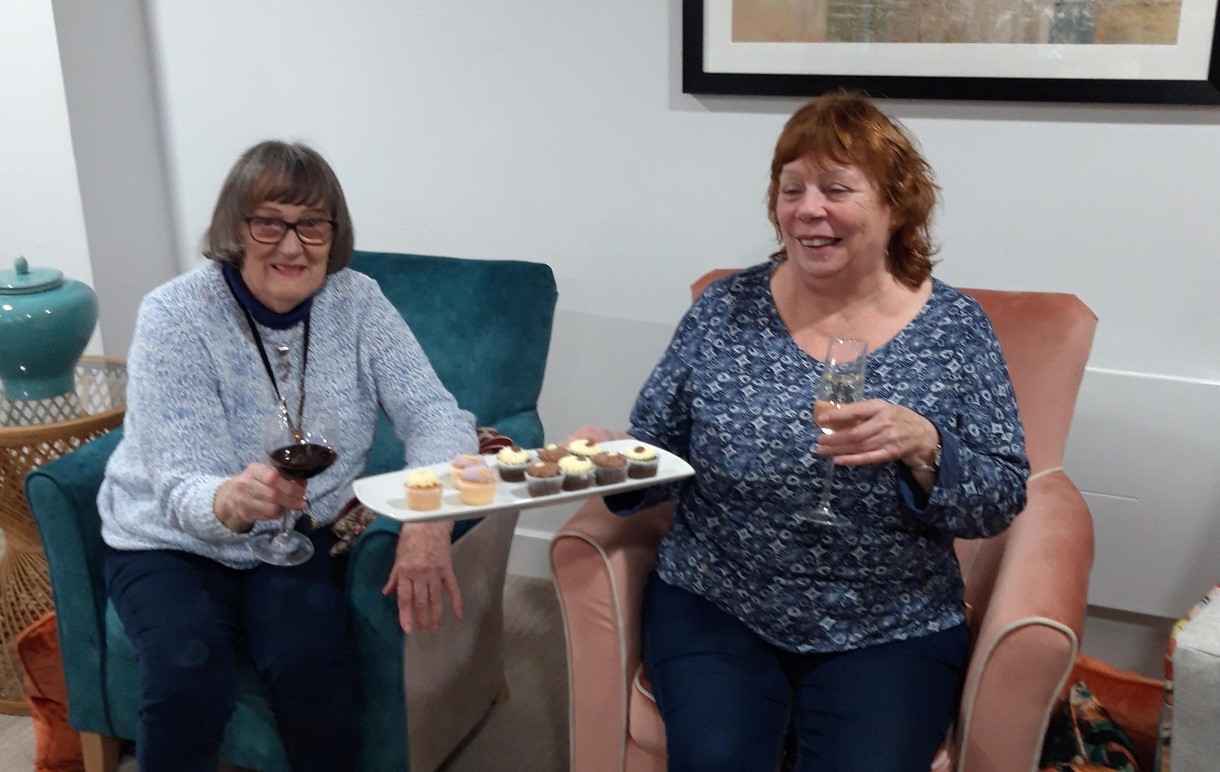 women sitting in chairs holding wine glasses