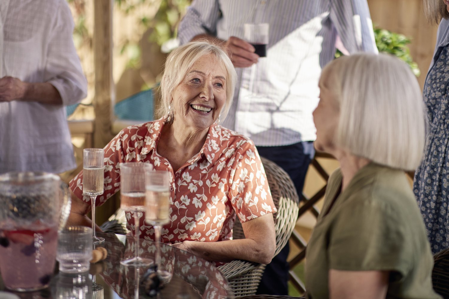 a person smiling at a table with glasses of wine