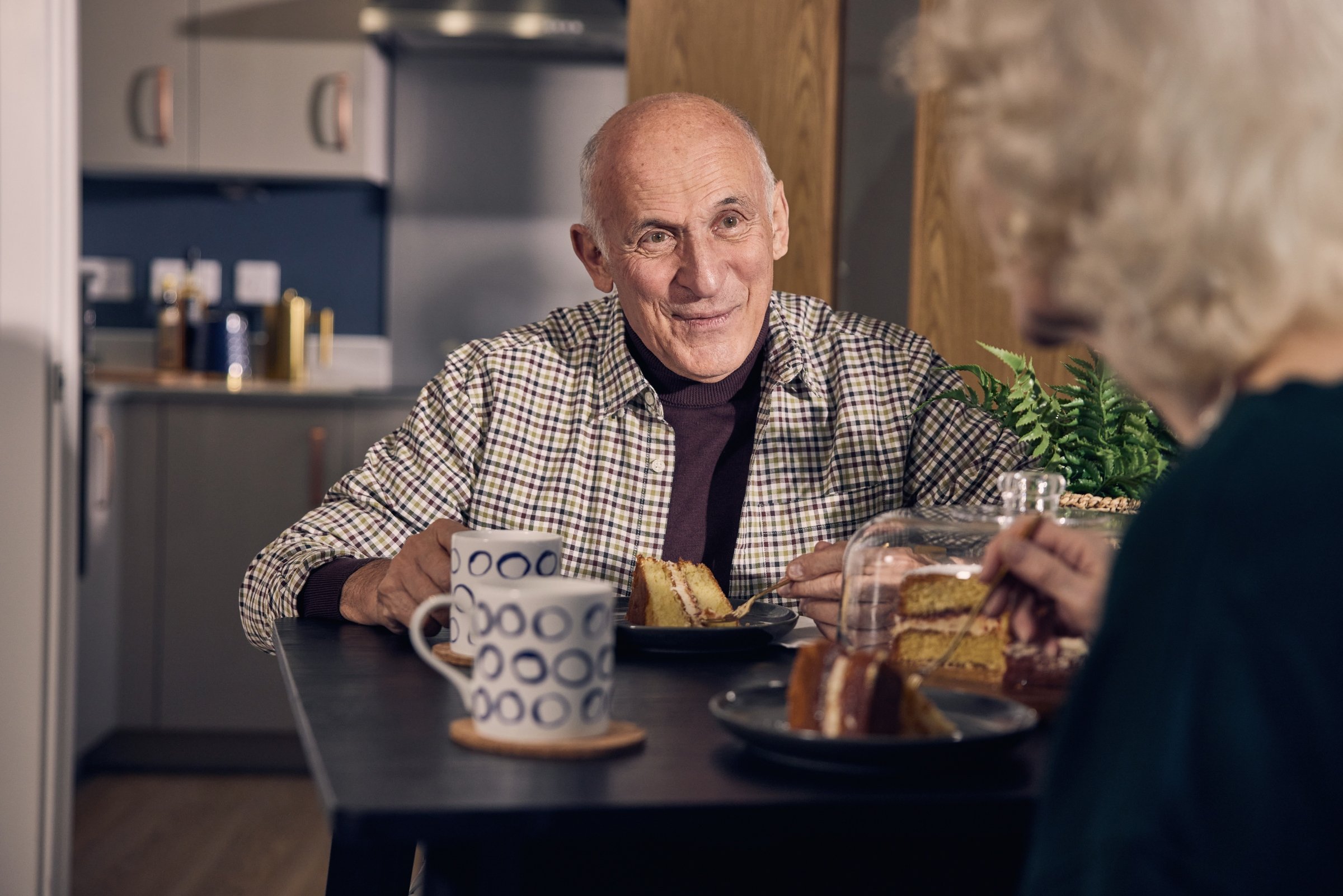 a man sitting at a table with food and a cup of coffee
