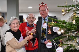 a group of people posing for a photo next to a christmas tree
