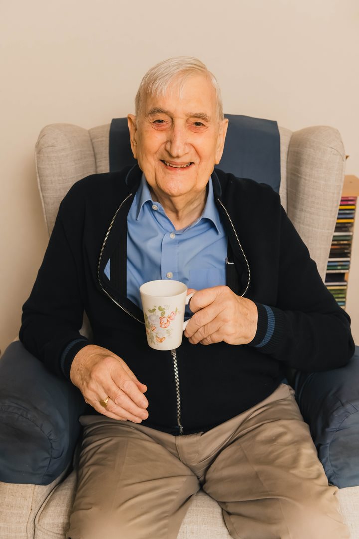 a person sitting on a couch holding a coffee cup