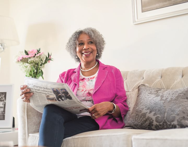 an old woman sitting on a couch reading a book