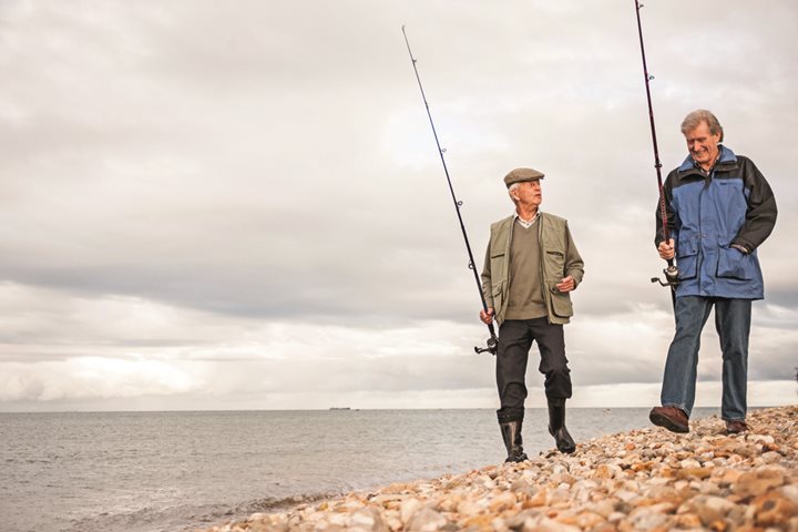 two men fishing on a rocky beach