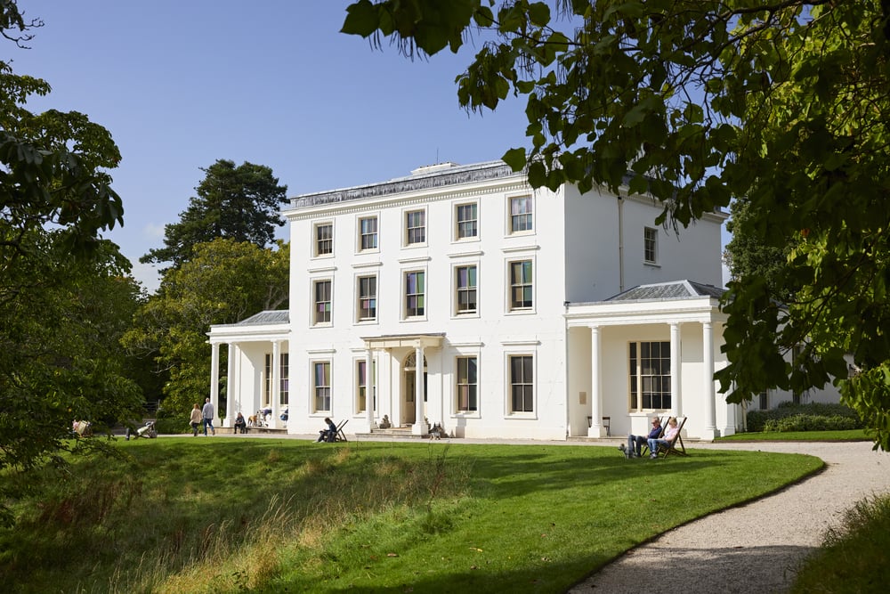 a white building with a lawn and trees in front of it