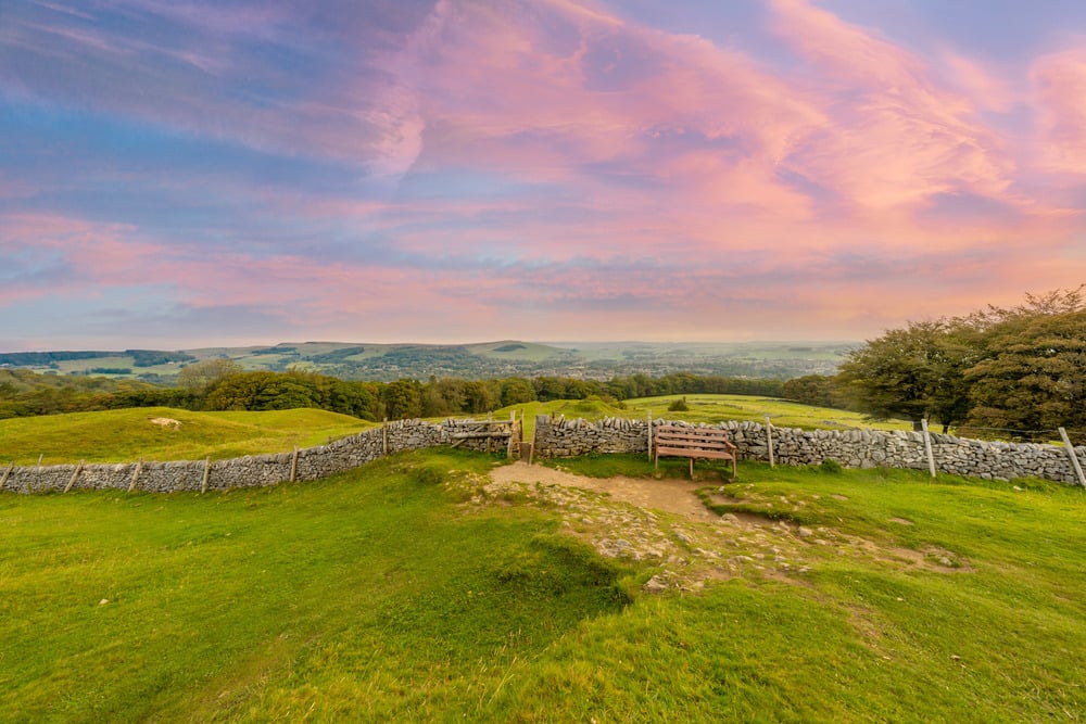 a fenced in field with a bench and a cloudy sky