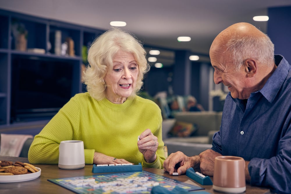 a man and a woman sitting at a table playing a board game