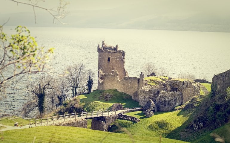 a castle on a hill with Urquhart Castle in the background