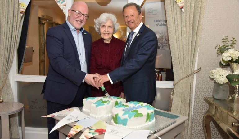 a couple of men cutting a cake