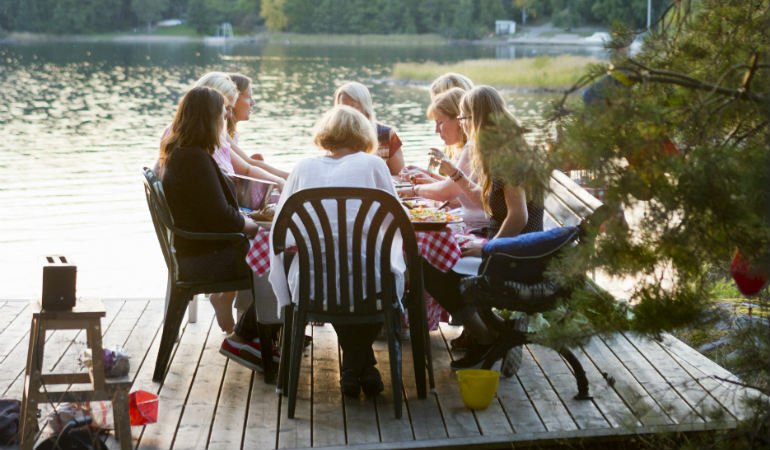 a group of people sitting on chairs on a deck overlooking a body of water