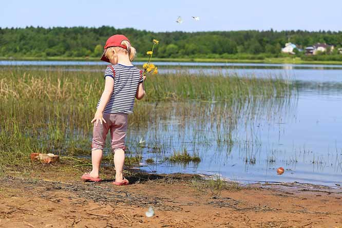 a child standing in front of a lake with a flower in her hair