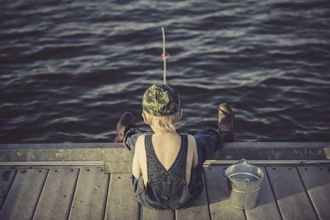 a person sitting on a dock with a dog and a dog