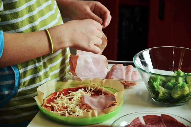 a person putting a piece of meat into a bowl of salad
