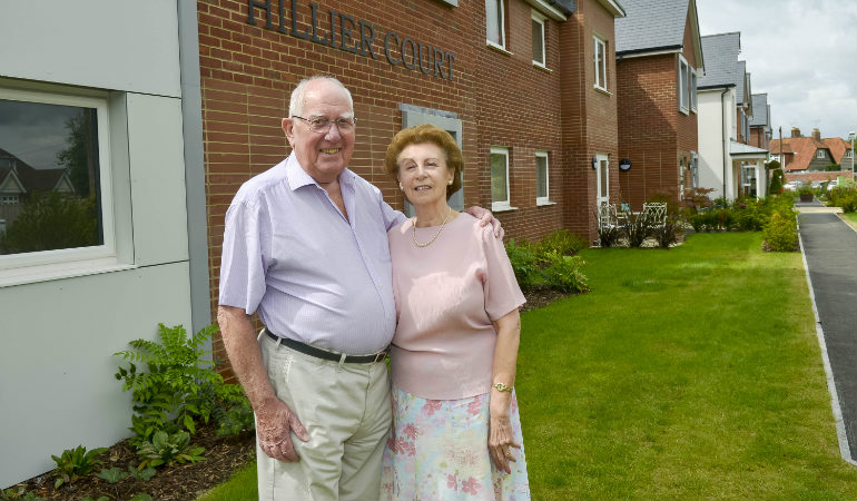 a man and woman standing in front of a brick building