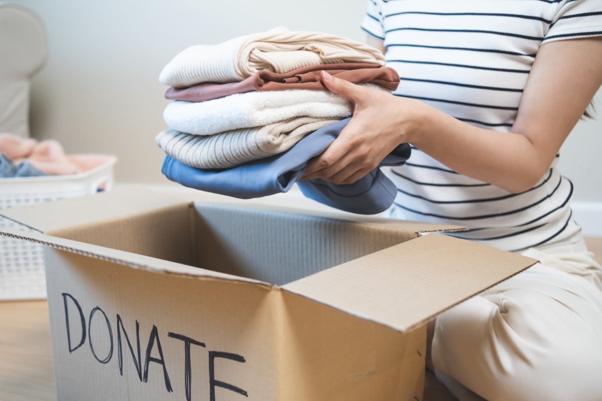 A woman putting clothes into a box labelled donate