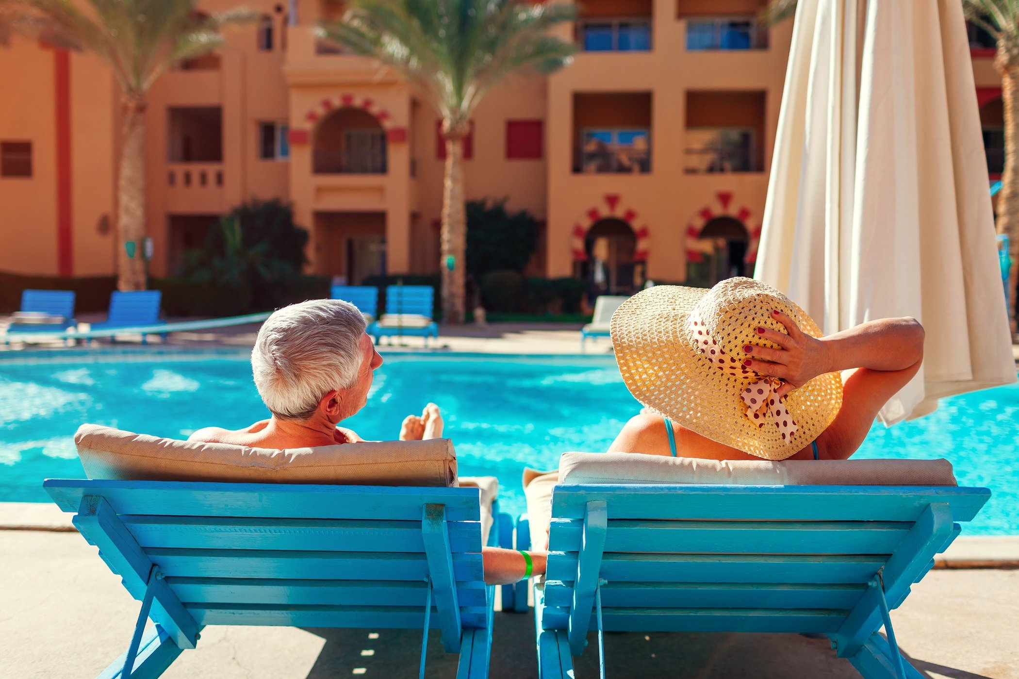 a person sitting in a chair by a pool with a straw hat