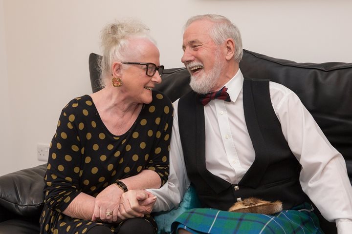 Jessie and Hugh laughing on the couch