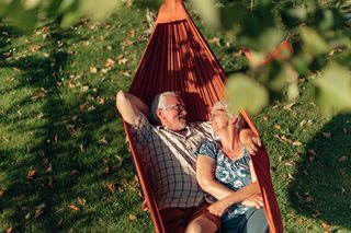 a man and woman sitting in a hammock in a yard