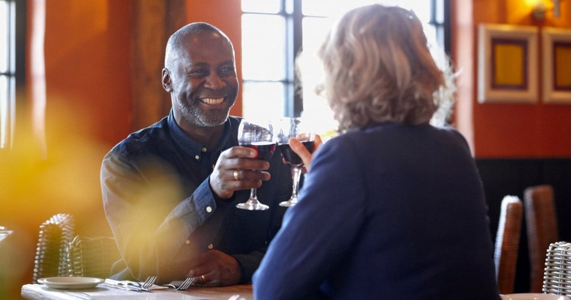 a man and a woman sitting at a table with wine glasses