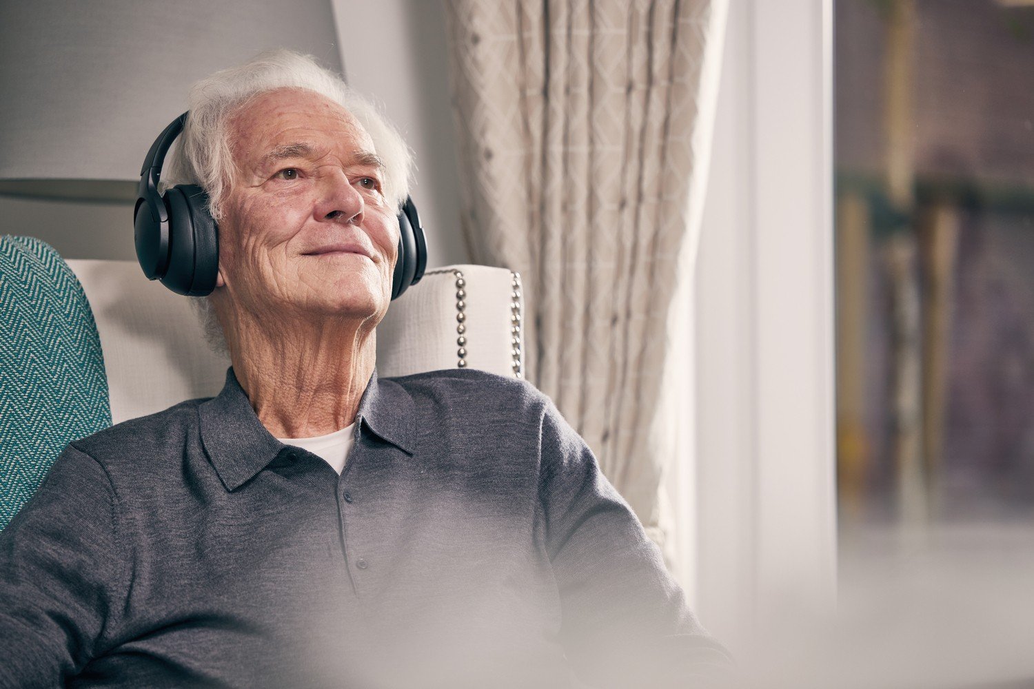 An older man relaxing and listening to music in a retirement home showing how to unwind and improve sleep quality.