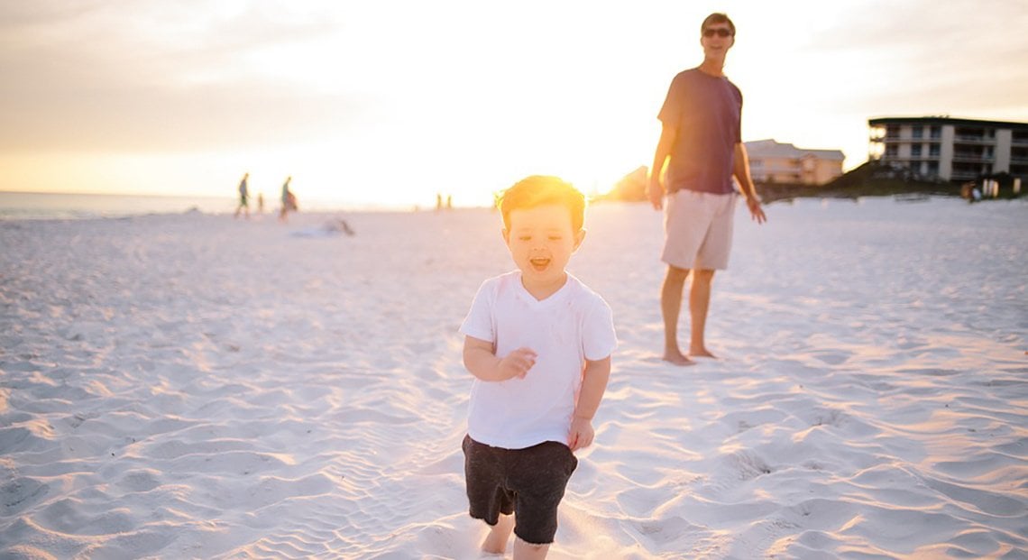 a man and a child walking on a beach