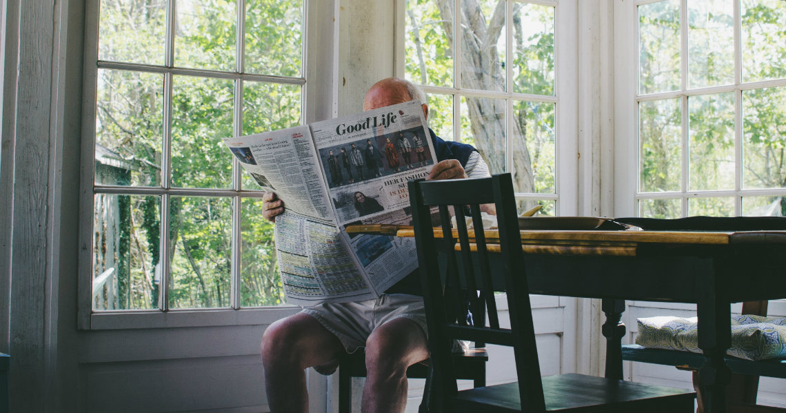 a person reading a newspaper on a bench
