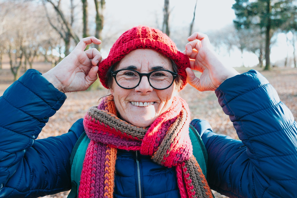 Over 60s retired woman wearing a hat and scarf to keep warm in colder weather.