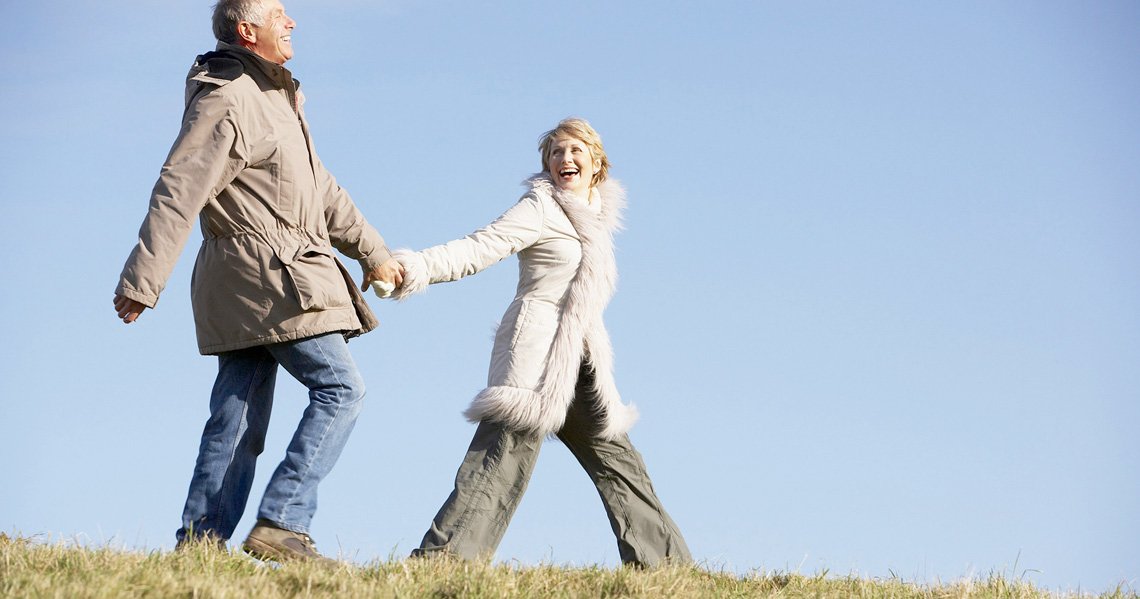 a man and woman holding hands and walking in a field