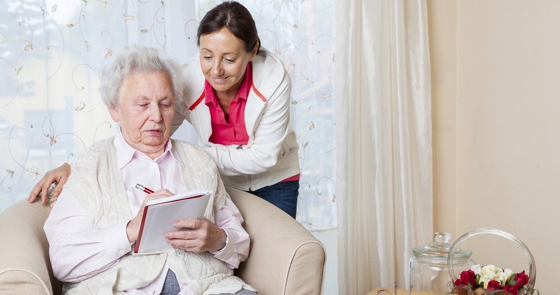 a man and woman sitting on a couch looking at a book