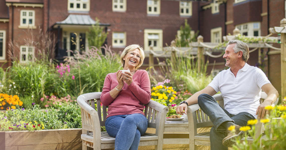 a man and woman sitting on a bench in a garden
