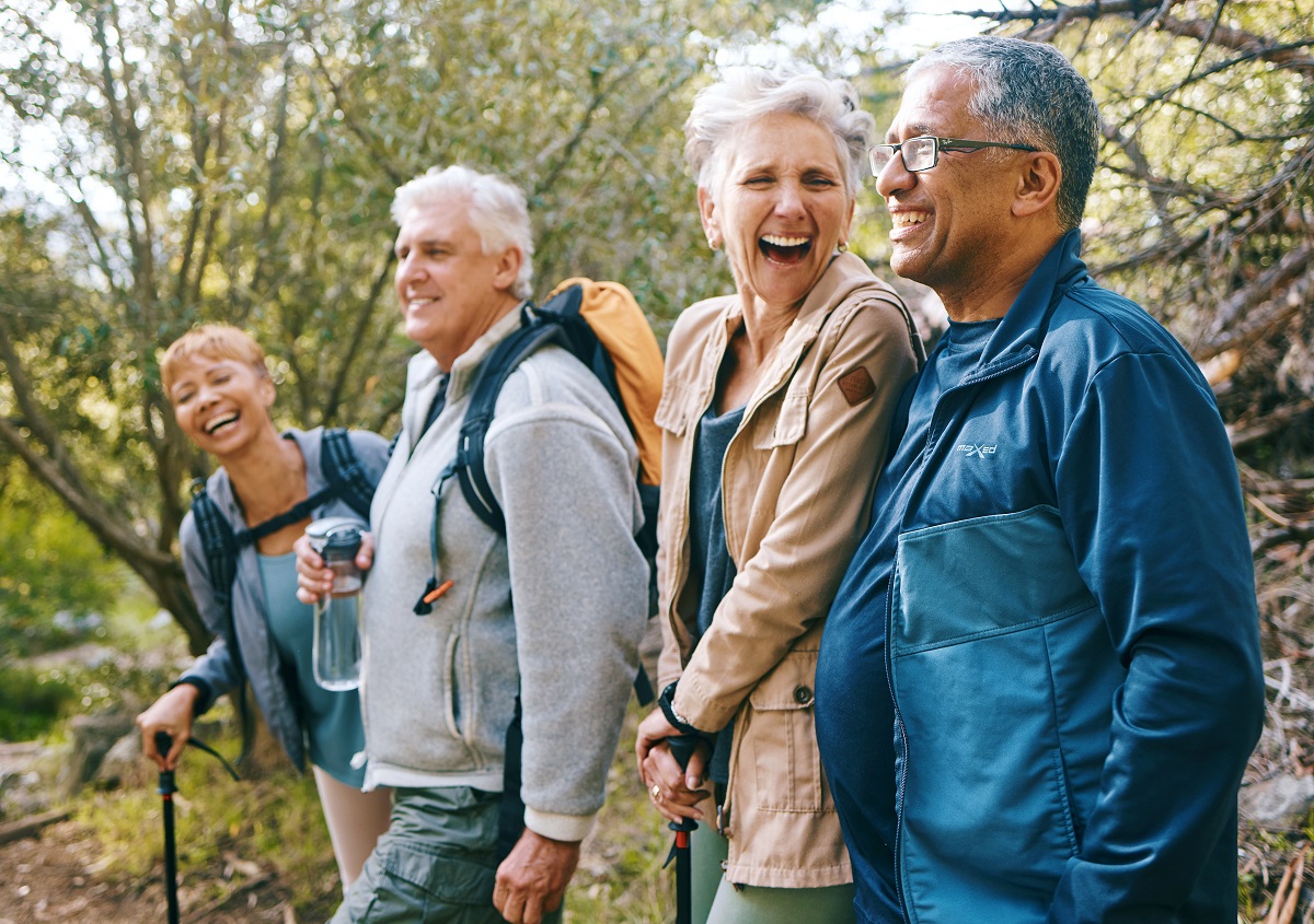 A group of four seniors, engrossed in conversation as they walk in nature