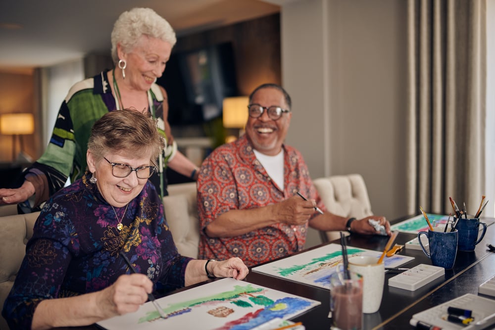 A group of seniors learning how to paint, laughing as they go