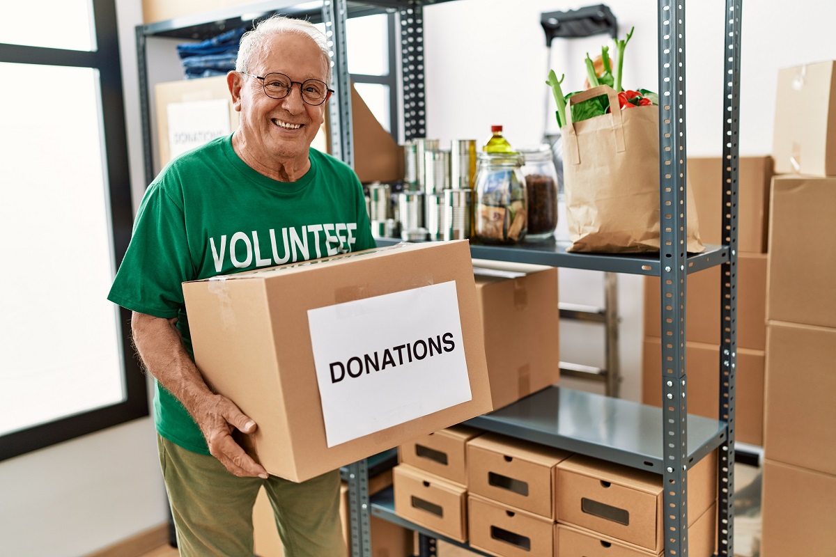 A senior volunteering for a charity, getting food donation boxes ready for those who need them