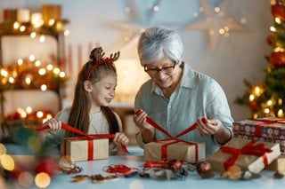 a woman and grandchild wrapping christmas gifts